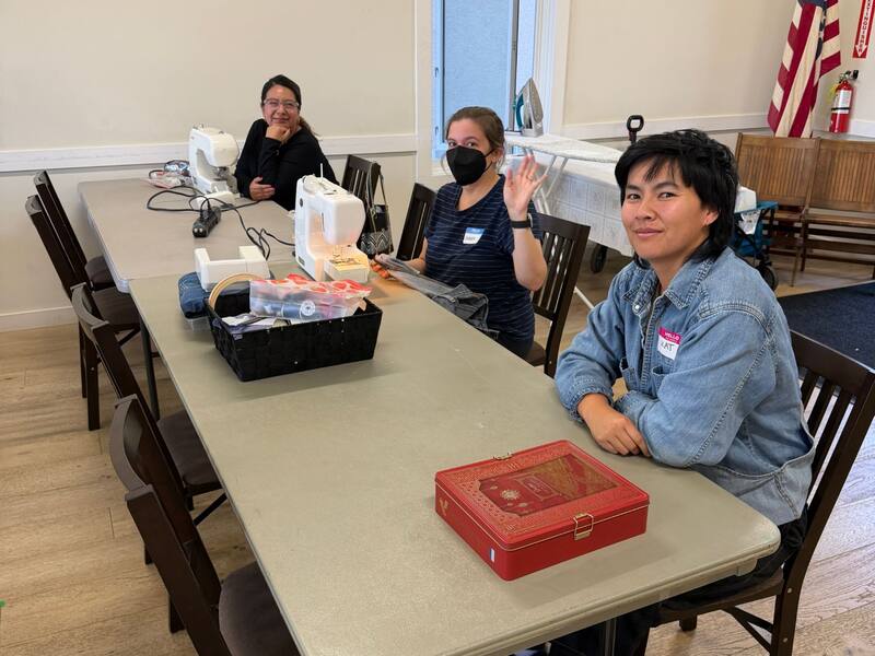 Sewing volunteers at the textile repair table with sewing machines