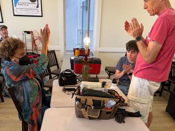 Volunteers and a visitor applauding a freshly repaired lamp